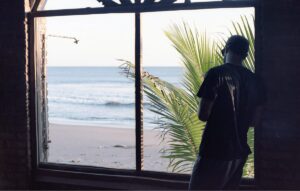 Ragazzo con cappello di spalle e finestra sul mare